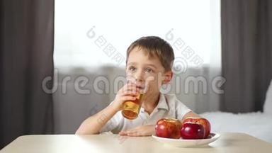 快乐的孩子坐在房间的桌子旁喝苹果汁。 <strong>儿童健康</strong>食品的概念
